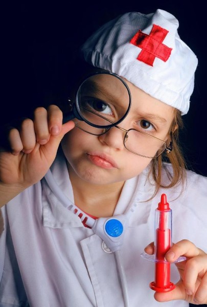 Ein Kind im weißen Arztkittel mit einer Spritze in der Hand